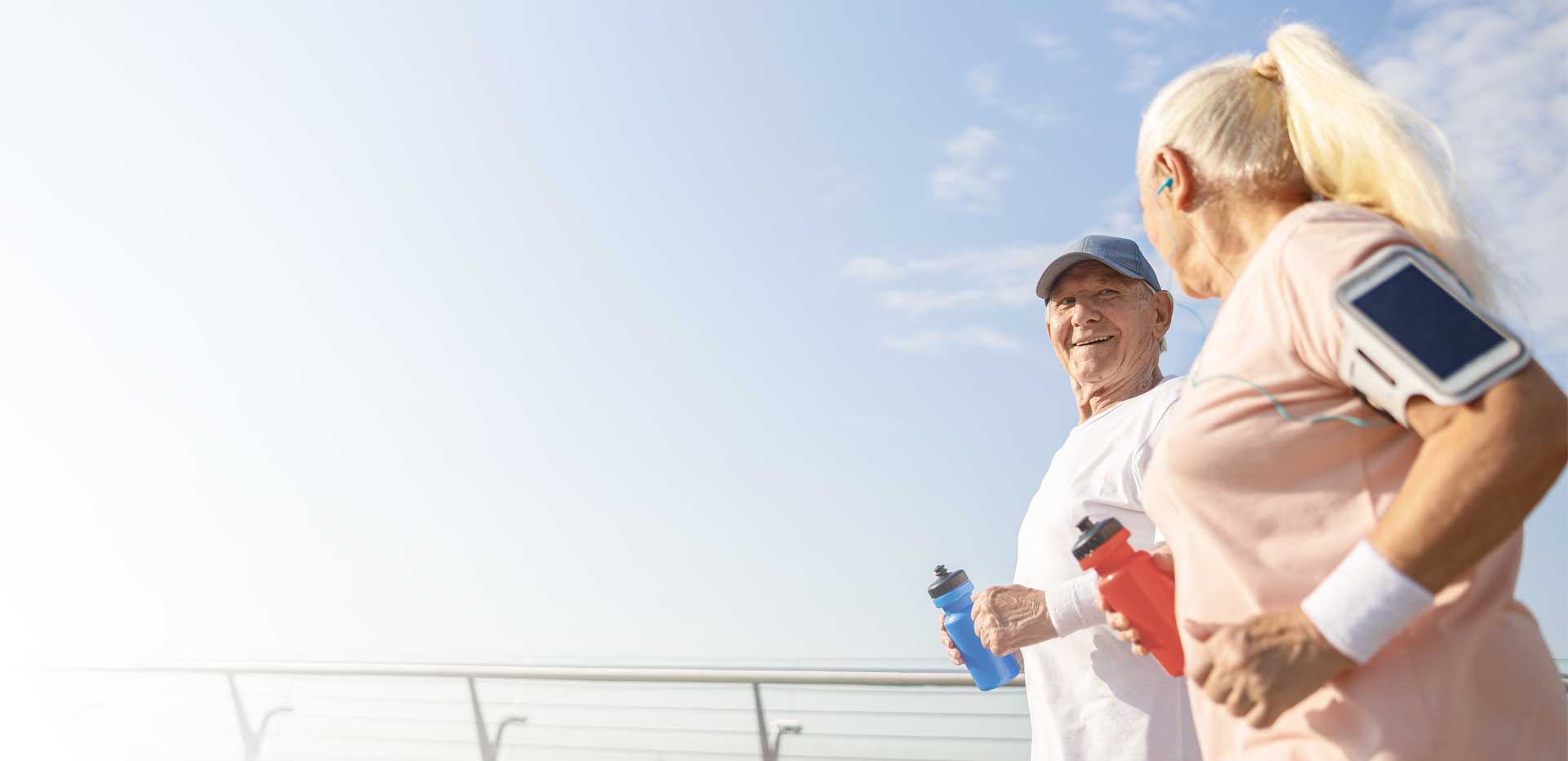 Älteres Paar ist am joggen, Mann lächelt zu seiner Frau.